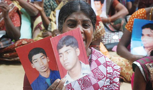 A Sri Lankan Tamil mother holds up pictures of hr two missing sons at a demonstration of families of missing persons. 