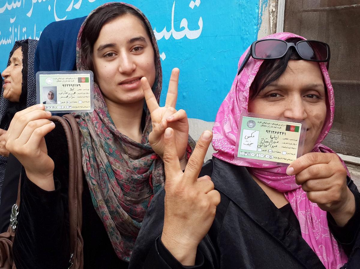 Afghan women produly display their identity cards which are necessary for voting.