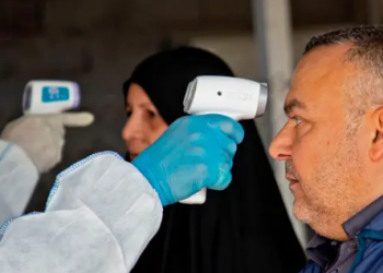 A member of a medical team takes a the temperature of Iraqi at the Shalamjah border crossing between Iran and Iraq on February 21, 2020. Hussein FALEH / AFP) (Photo by HUSSEIN FALEH/AFP via Getty Images