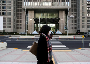 A woman wearing a protective face mask, following an outbreak of the coronavirus, walks past banners of the upcoming Tokyo 2020 Olympic and Paralympic Games outside the Tokyo Metropolitan Government building in Tokyo, Japan, February 28, 2020. REUTERS/Athit Perawongmetha/File Photo