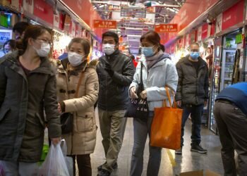 People wear face masks as they shop at a market in Beijing, March 14, 2020. (AP/Mark Schiefelbein)