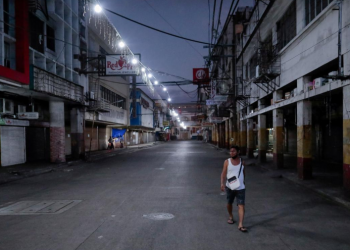 A man wearing a protective mask on his neck walks past closed shops in an empty street following the lockdown in the Philippine capital to prevent the spread of the coronavirus disease (COVID-19), in Manila, Philippines, March 24, 2020. REUTERS/Eloisa Lopez/