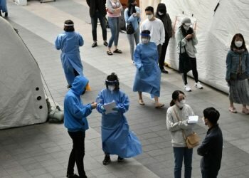 Medical staff members (in blue gowns) guide visitors waiting to take the coronavirus test in Itaewon, Seoul, on May 12, 2020.PHOTO: AFP