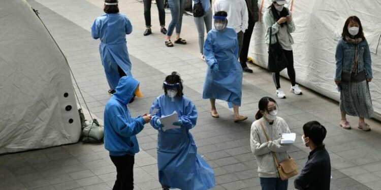 Medical staff members (in blue gowns) guide visitors waiting to take the coronavirus test in Itaewon, Seoul, on May 12, 2020.PHOTO: AFP