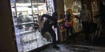 People run out of a smoke shop with smoking instruments after breaking in as police arrive on June 1 in New York City, New York.