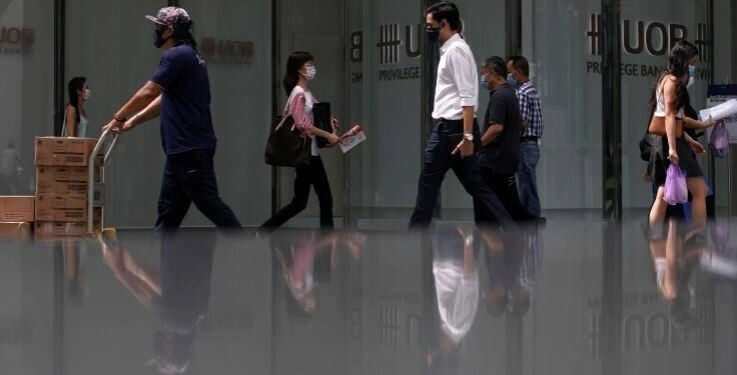 People wearing protective masks as a precaution against COVID-19 walk during lunch hour at the central business district in Singapore,