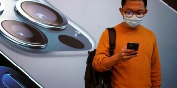 FILE PHOTO: A man wears a face mask while waiting at an Apple Store before Apple's 5G new iPhone 12 go on sale, as the coronavirus disease (COVID-19) outbreak continues in Shanghai China October 23, 2020. REUTERS/Aly Song/File Photo