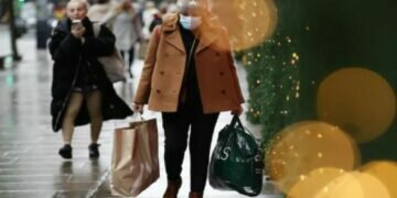 A woman wearing a face mask to guard against Covid-19 carries bags of shopping along Oxford Street in London. (Photo: AP)
