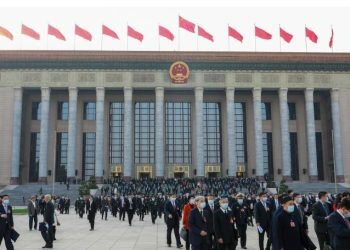 People walk in front of the Great Hall of the People on March 4, 2023, in Beijing, as the annual gathering known as the Two Sessions gets underway.