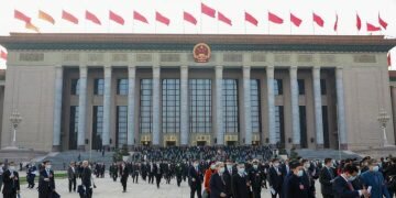 People walk in front of the Great Hall of the People on March 4, 2023, in Beijing, as the annual gathering known as the Two Sessions gets underway.