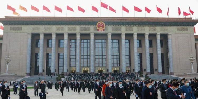 People walk in front of the Great Hall of the People on March 4, 2023, in Beijing, as the annual gathering known as the Two Sessions gets underway.