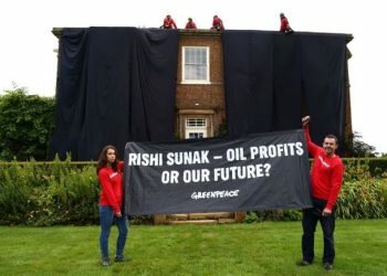 Greenpeace activists hold a banner while others cover British Prime Minister Rishi Sunak's £2m manor house in oil-black fabric in protest of his backing for a major expansion of North Sea oil and gas drilling amidst a summer of escalating climate impacts, in Yorkshire, Britain August 3, 2023.